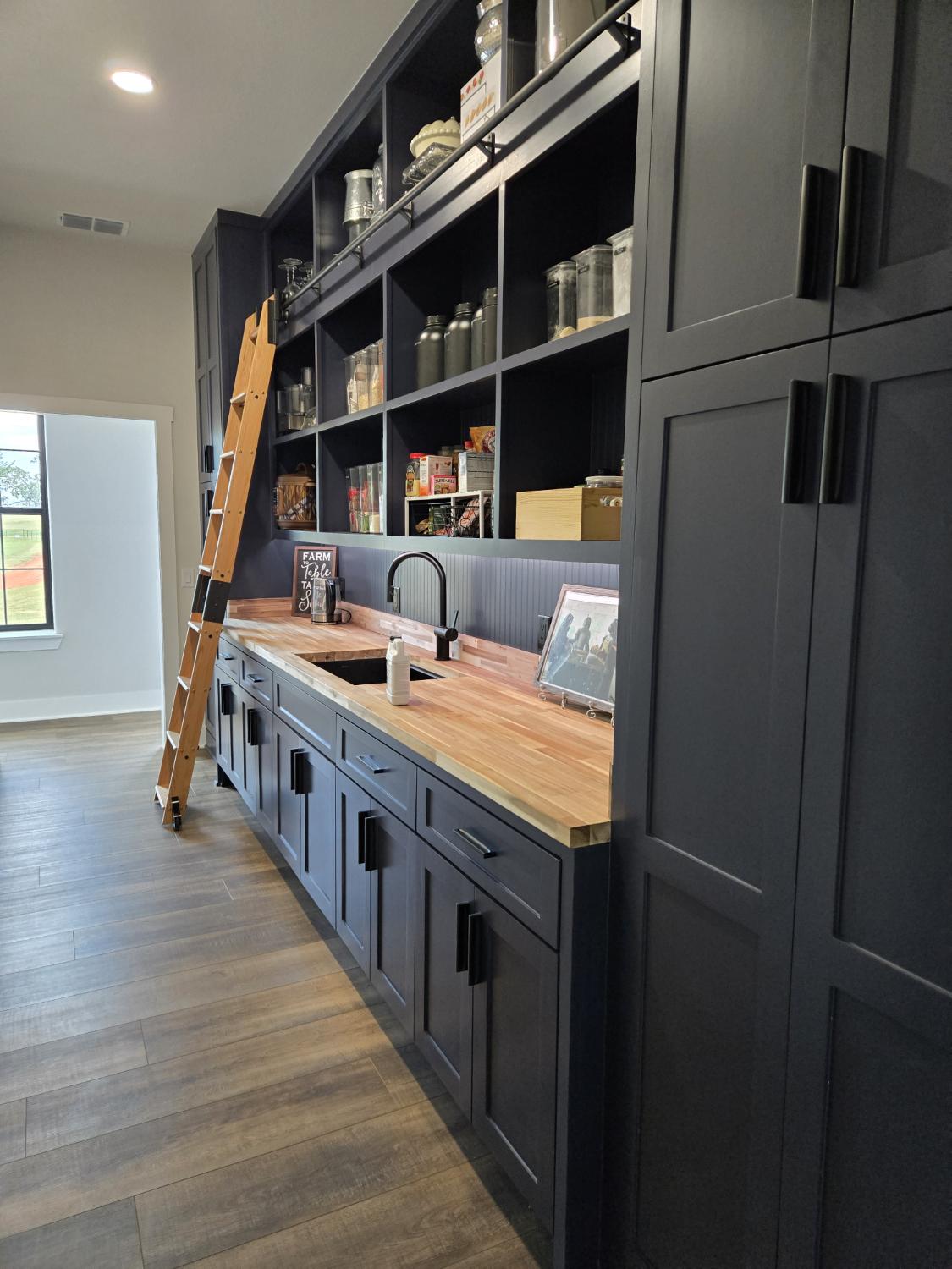 Navy pantry with a rolling ladder and butcher-block counter
