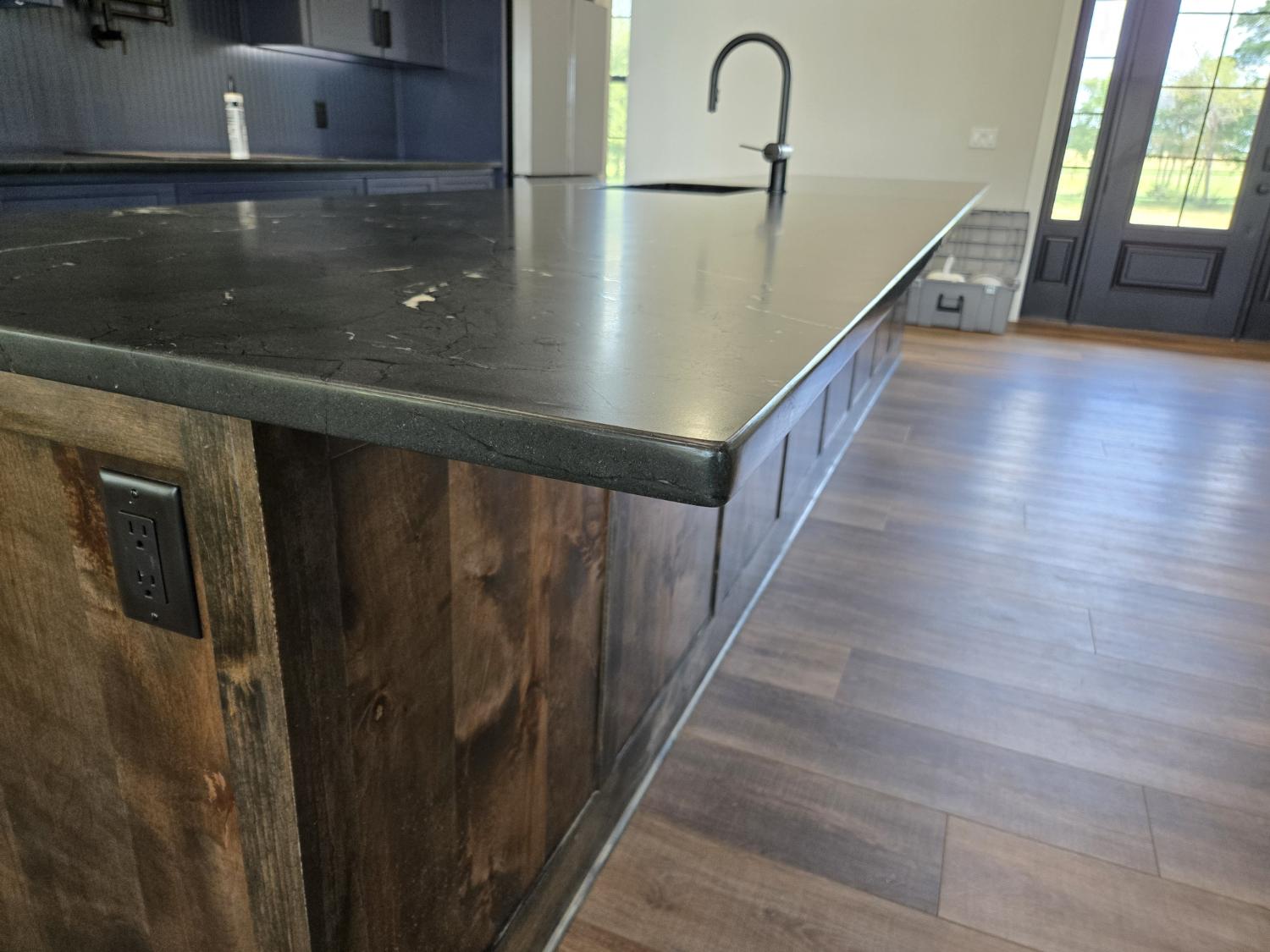 Eased edge on a Black Diamond quartzite island with a wood base and black outlet