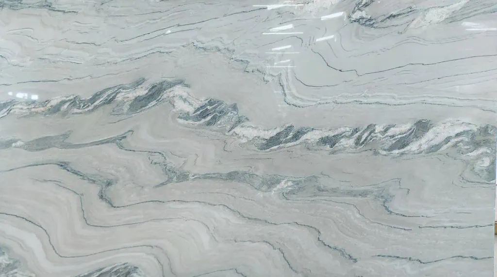 Close-up of a marble surface with swirling patterns in shades of gray and white. The design resembles flowing waves and has a glossy finish, reflecting light in some areas.