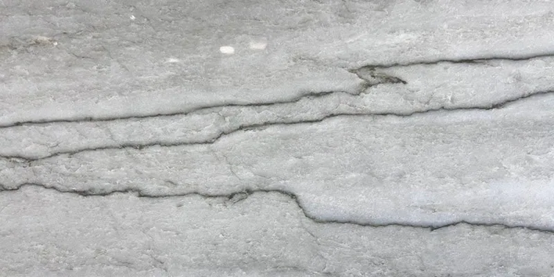 Close-up view of a light gray marble surface with natural, irregular dark gray veining running horizontally across. Ideal for kitchen remodeling, the texture appears smooth with subtle variations in tone, creating a refined and elegant appearance.