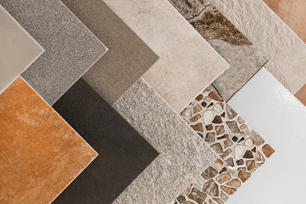 A variety of square tile samples are displayed, showcasing different colors and textures, including smooth, speckled, and mosaic patterns in shades of brown, gray, beige, black, and white.